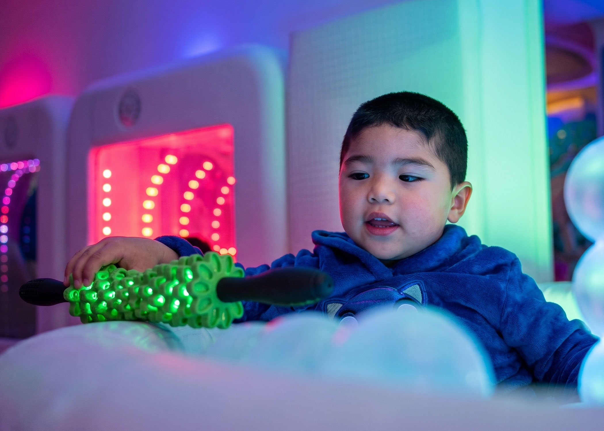 Niño en cuarto multisensorial con luz y juguetes terapéuticos